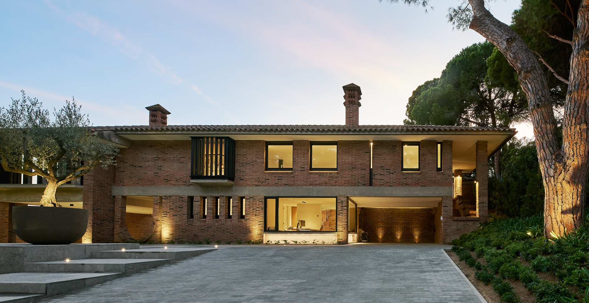 brick villa in twilight with enlightened interiors
