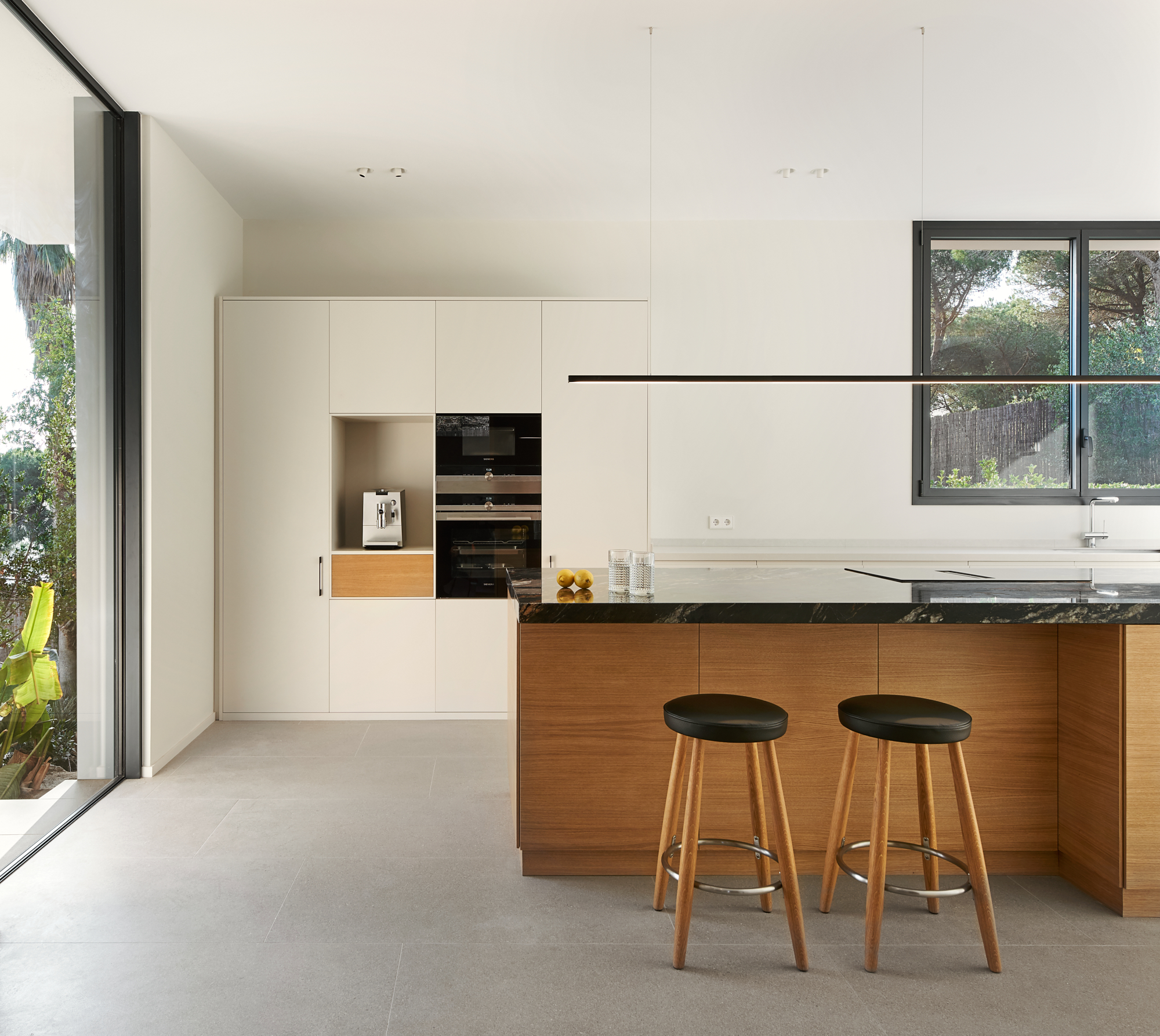 a kitchen island with two barstools with a view of the garden