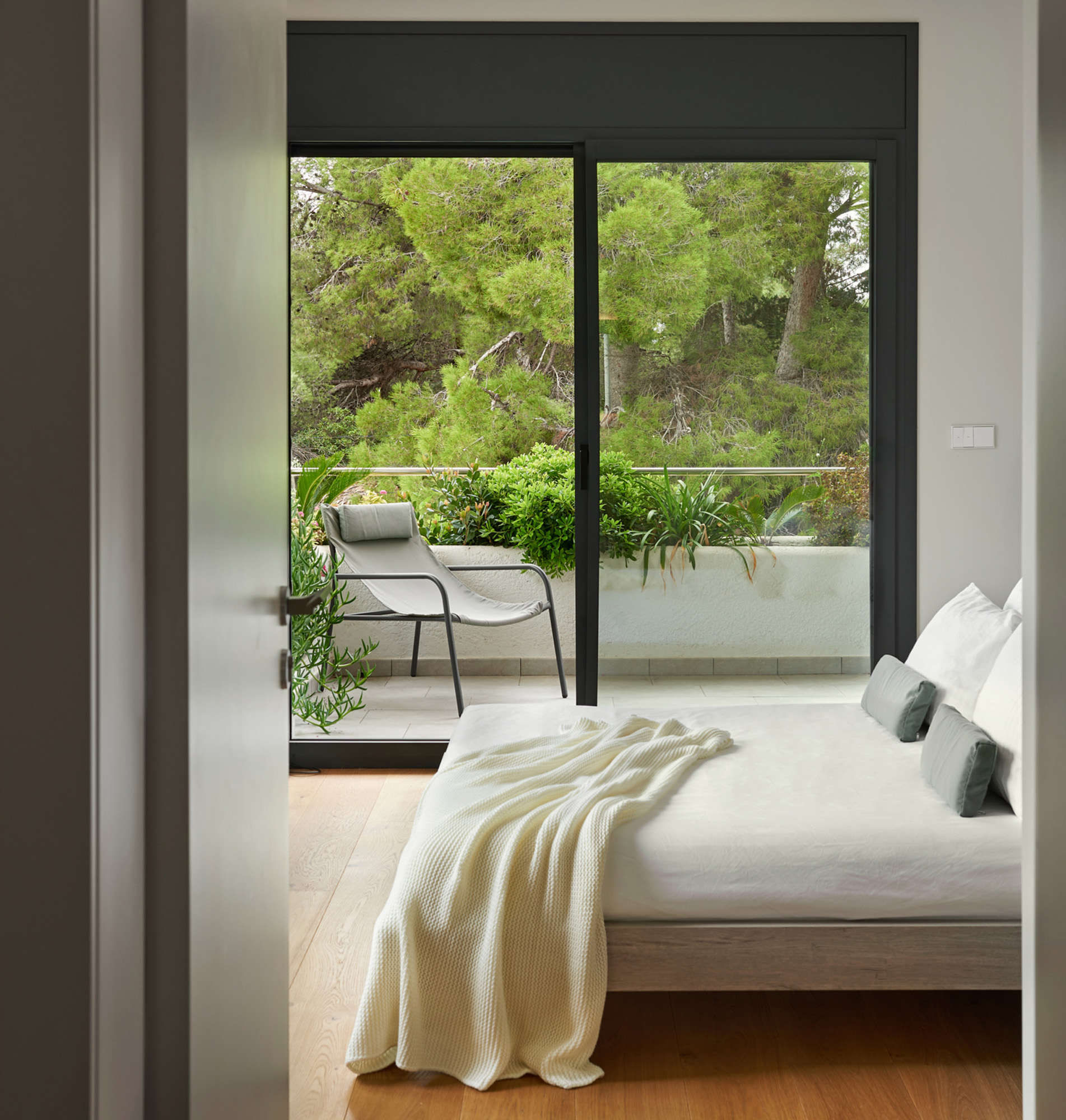 modern bedroom seen through a open door having a balcony in the back